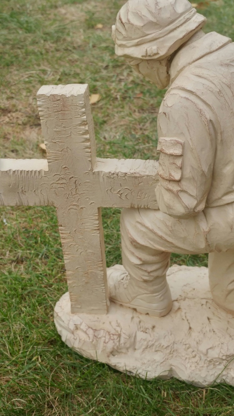 soldier kneeling at cross statue