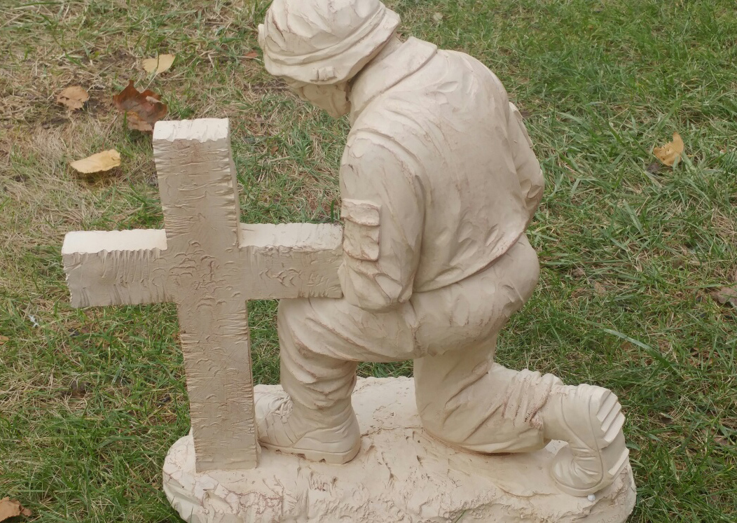 soldier kneeling at cross statue